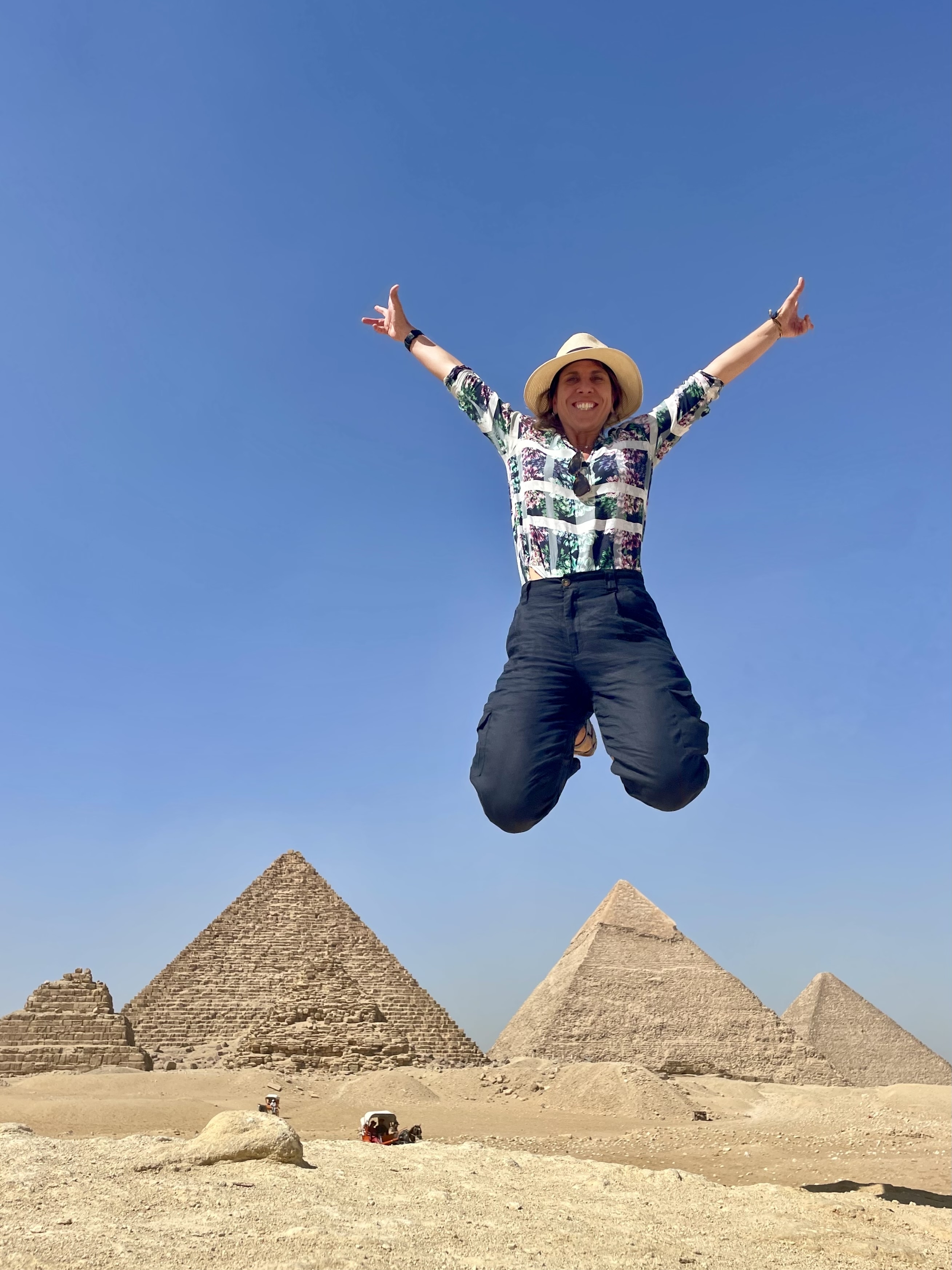 Person jumping with pyramids in the background.