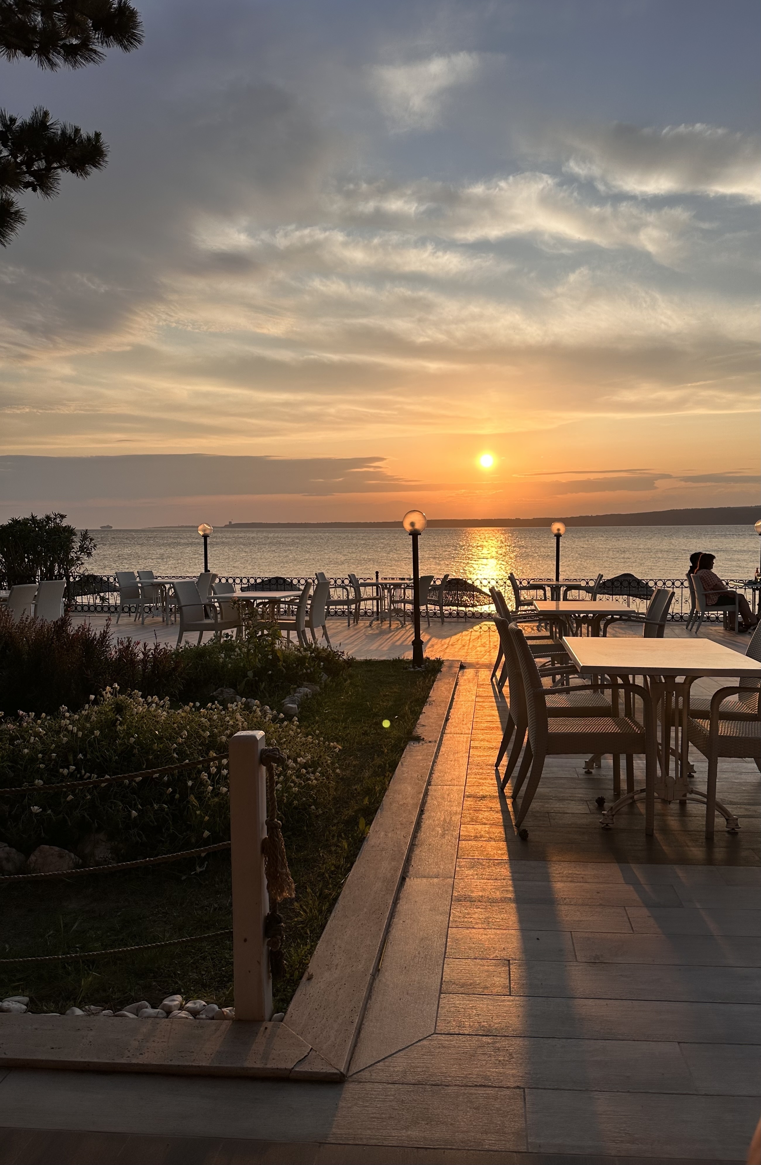 A sunset view over a serene waterfront with outdoor seating.
