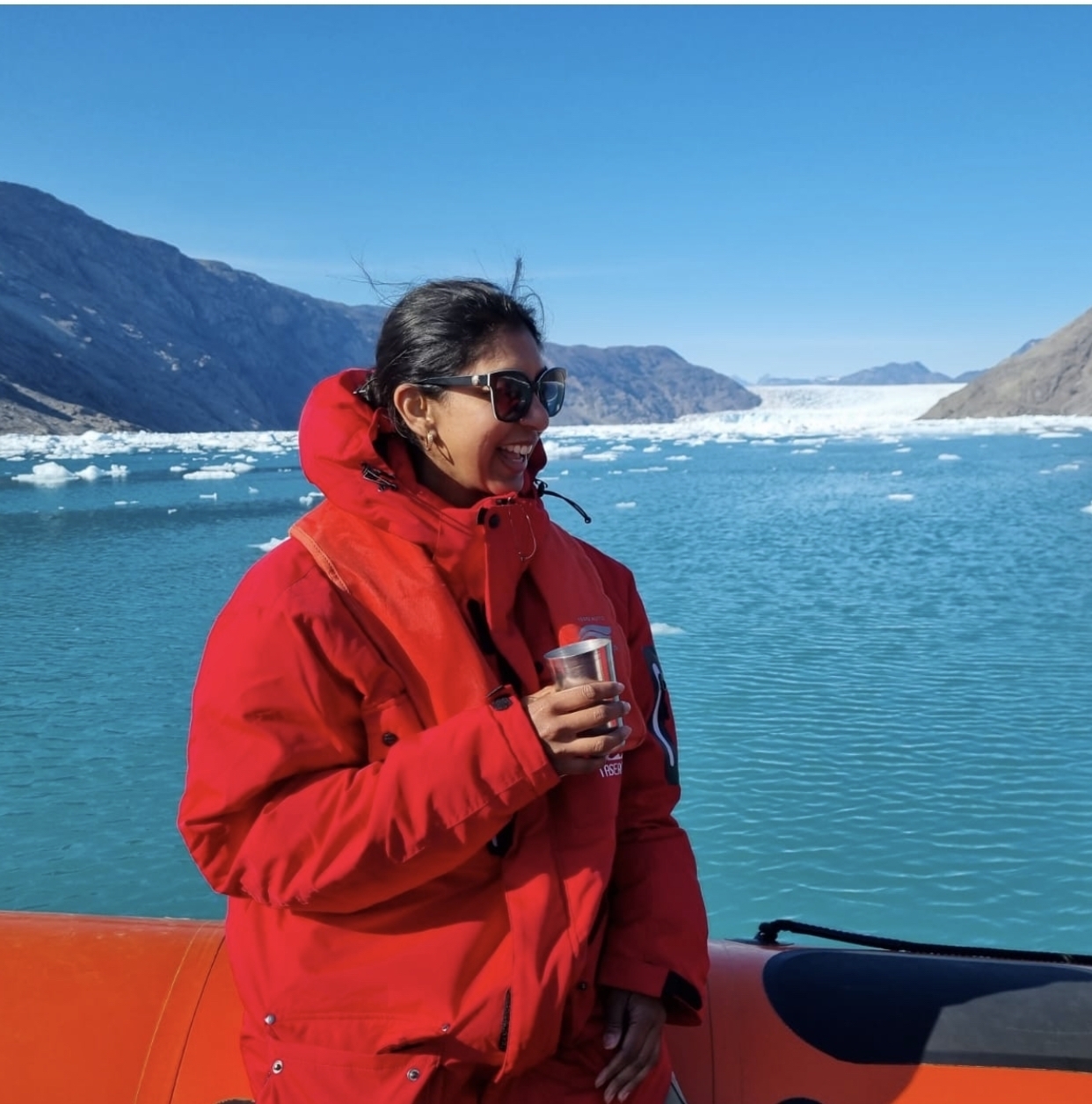 Person in red jacket standing with a glacier in the background.