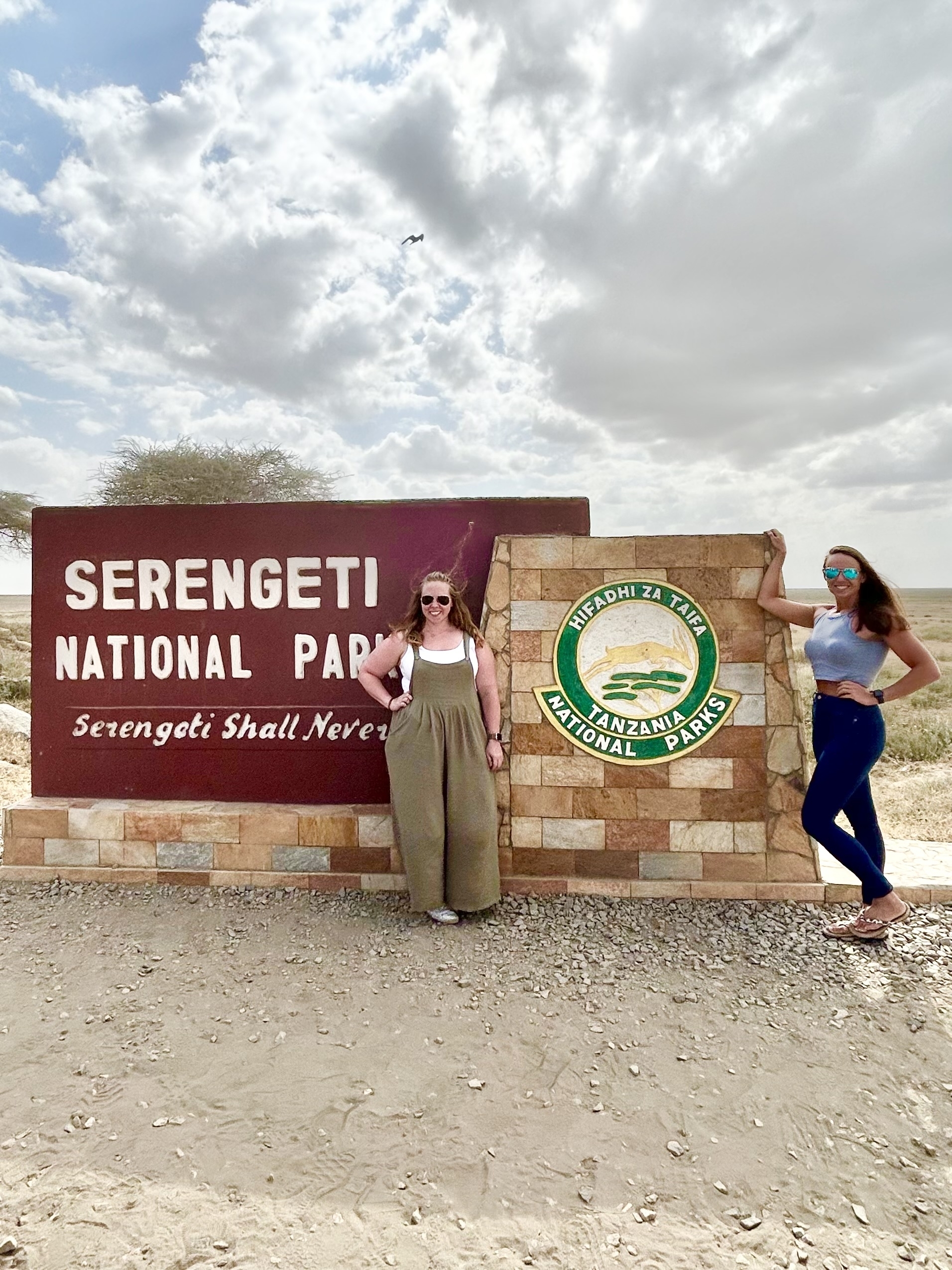 Two women posing with a Serengeti National Park sign.