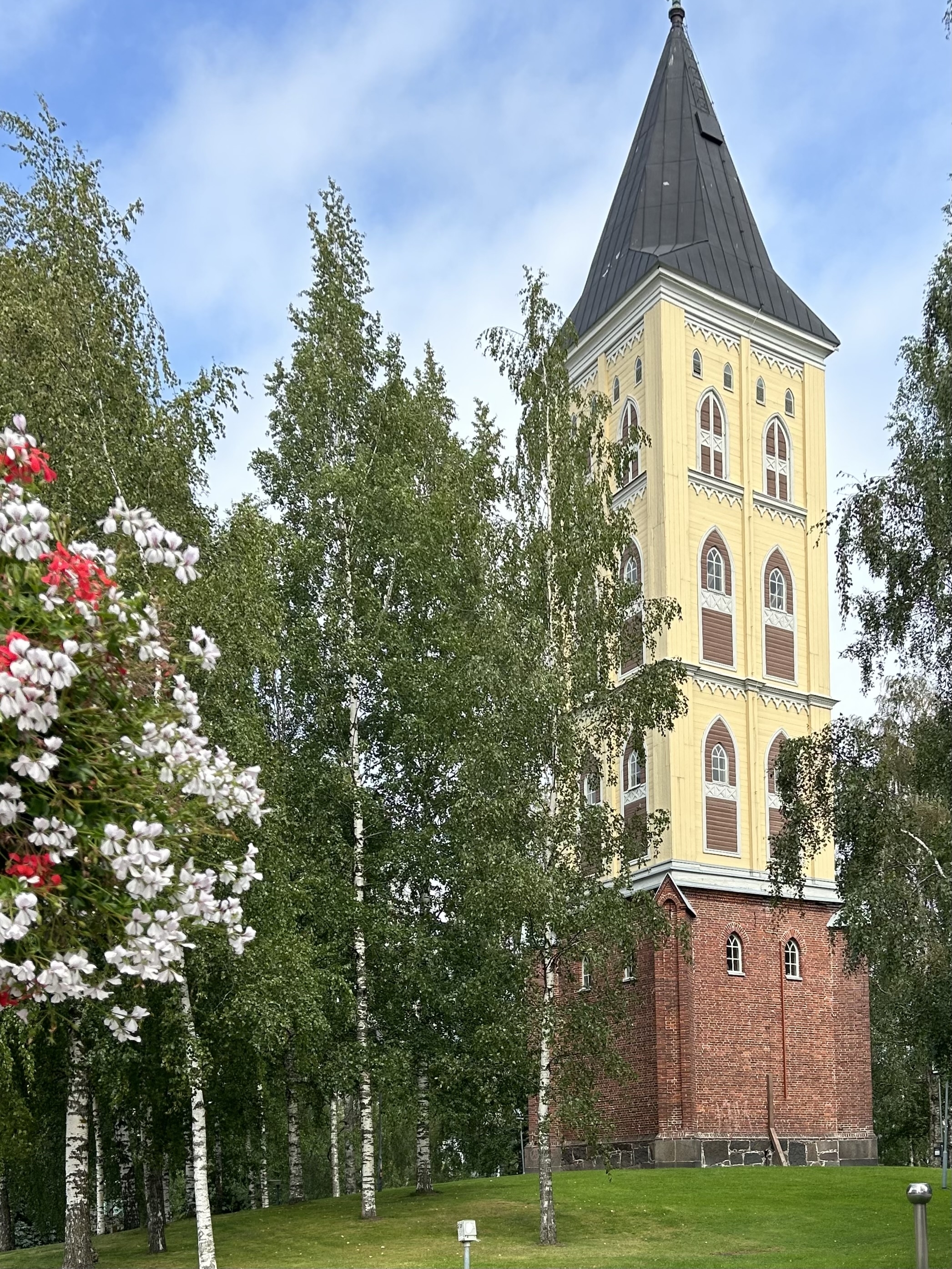 Tall, yellow church tower surrounded by trees.