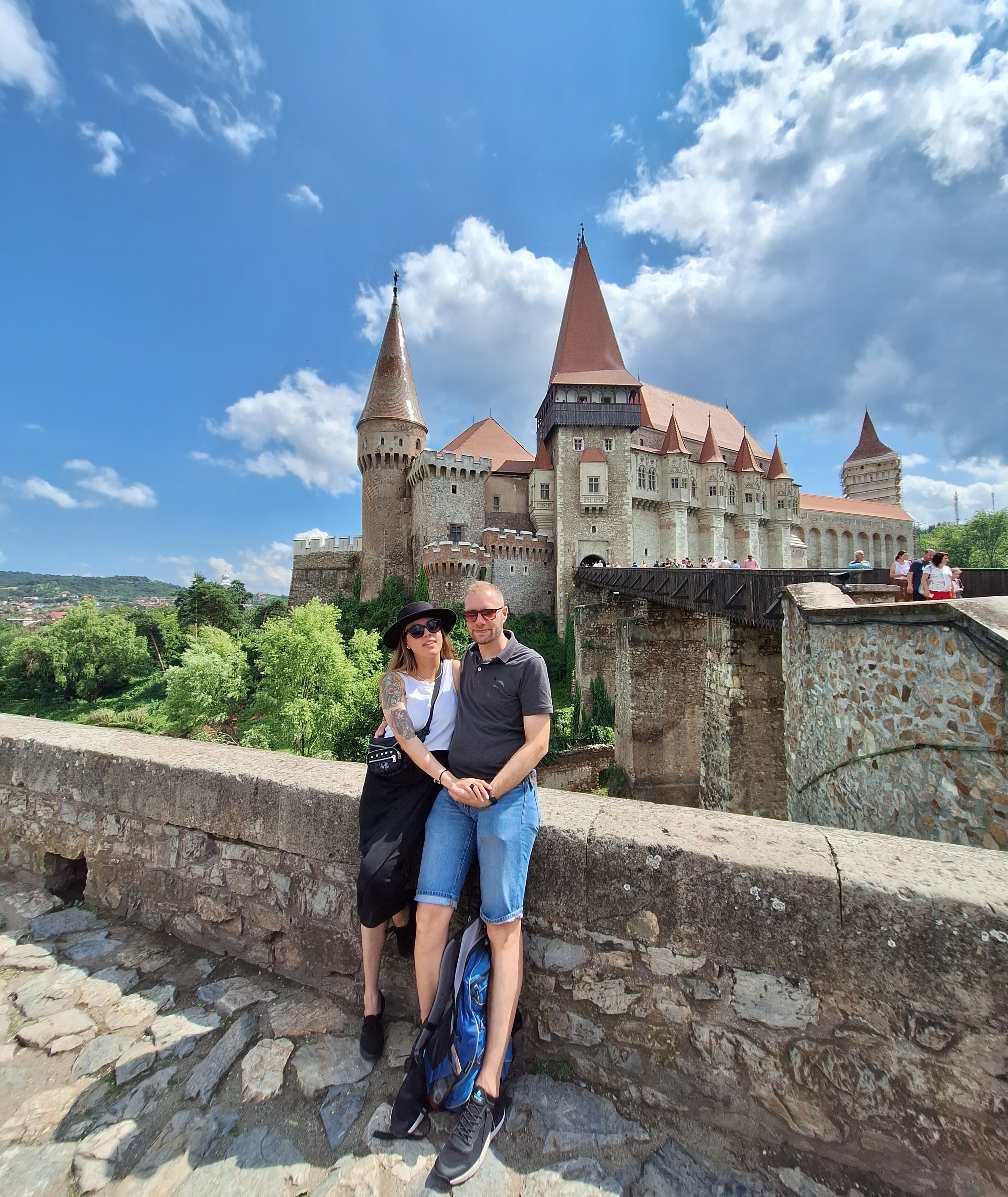 Couple posing in front of the large and historic Hunedoara Castle.