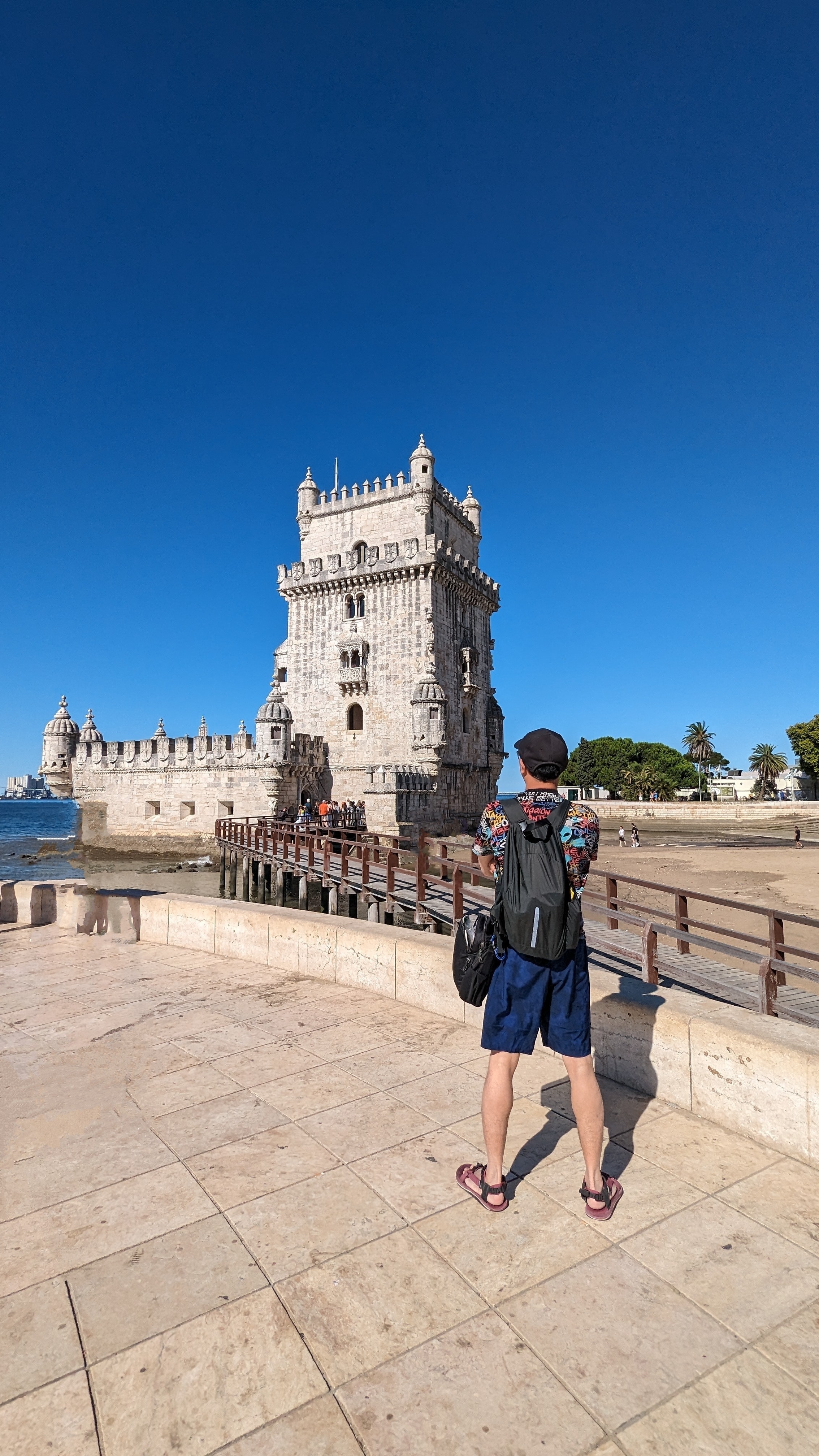 Person in front of the Belem Tower on a sunny day.