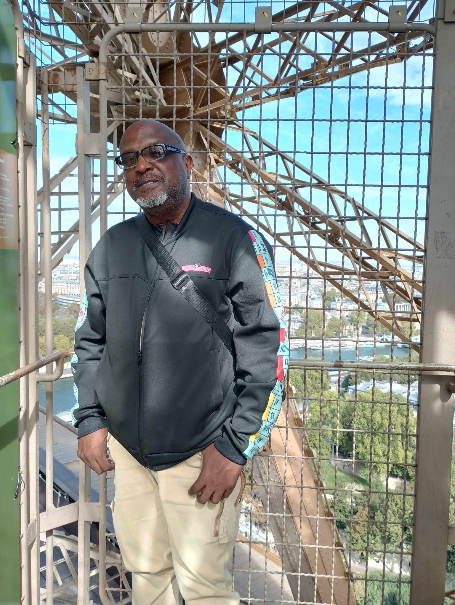 Person standing on the Eiffel Tower with city view.