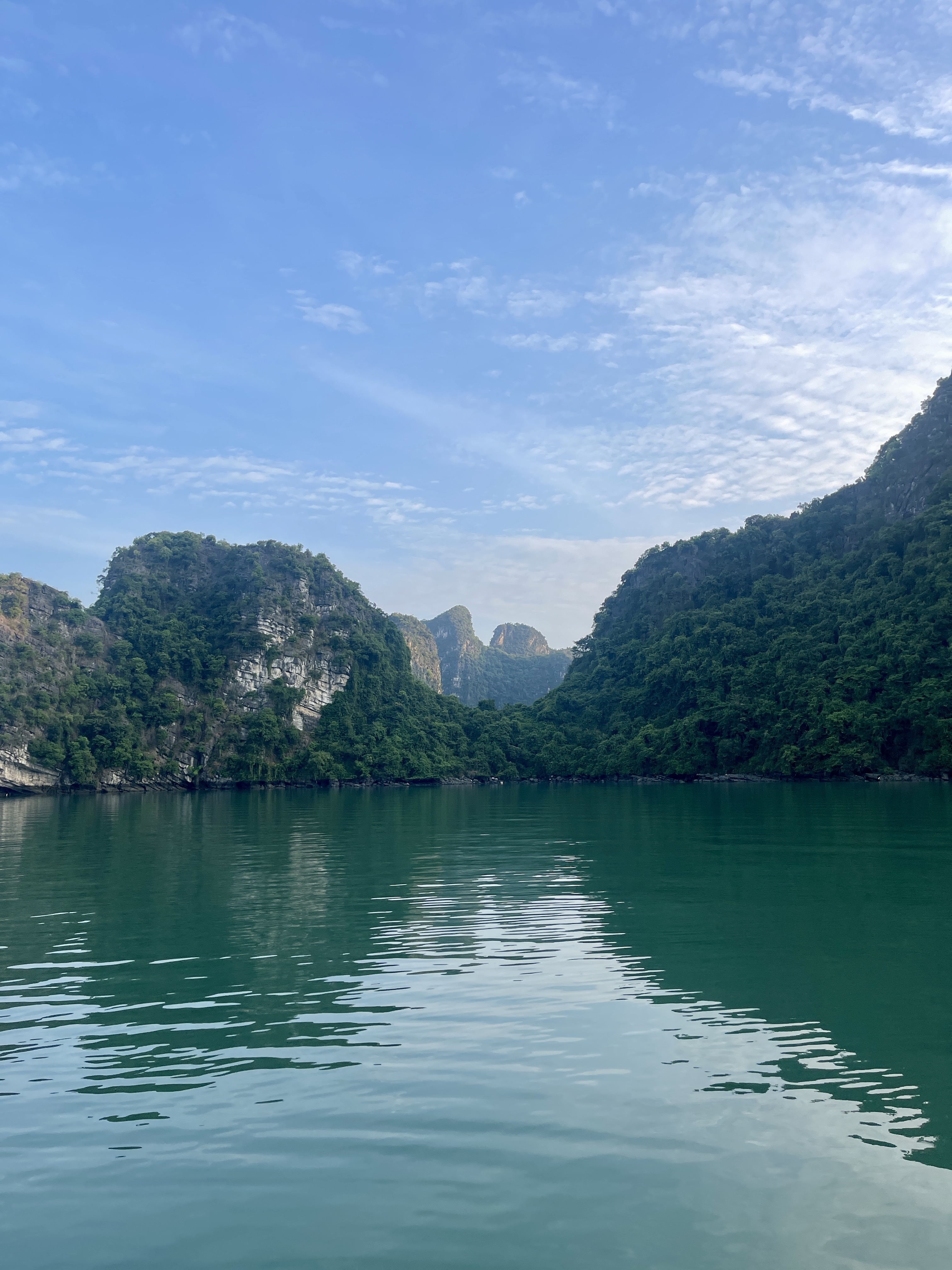 Dramatic limestone hills and green water under a blue sky.