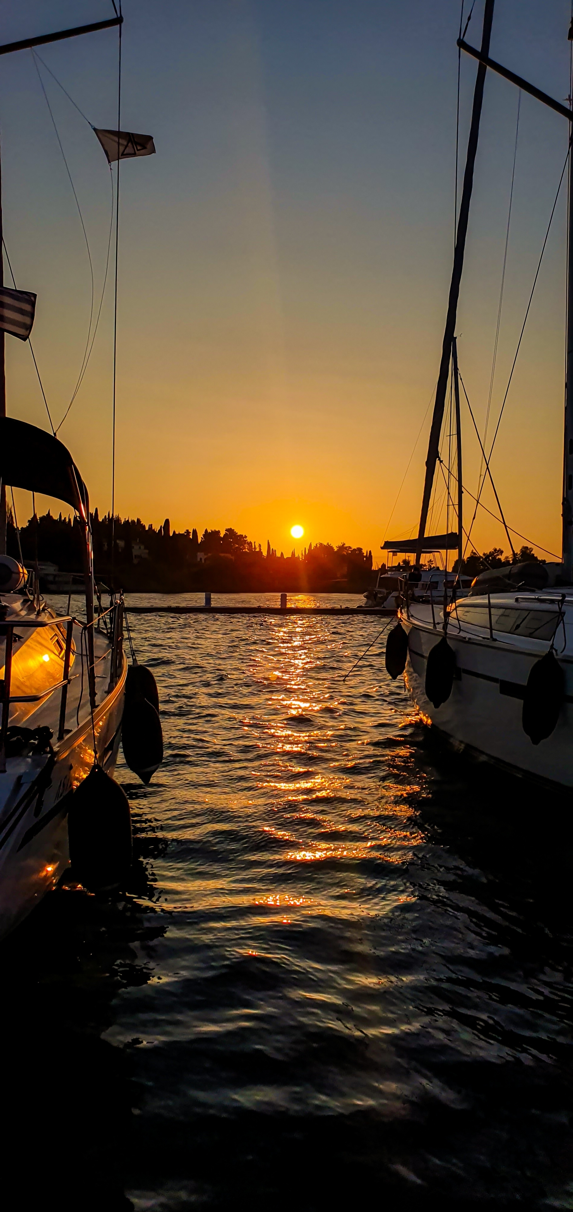 Sunset over the sea with silhouetted boats.