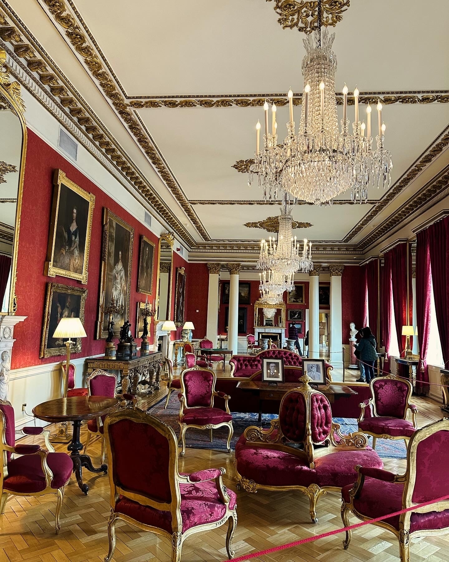 Luxurious interior of a historic building with chandeliers and paintings.