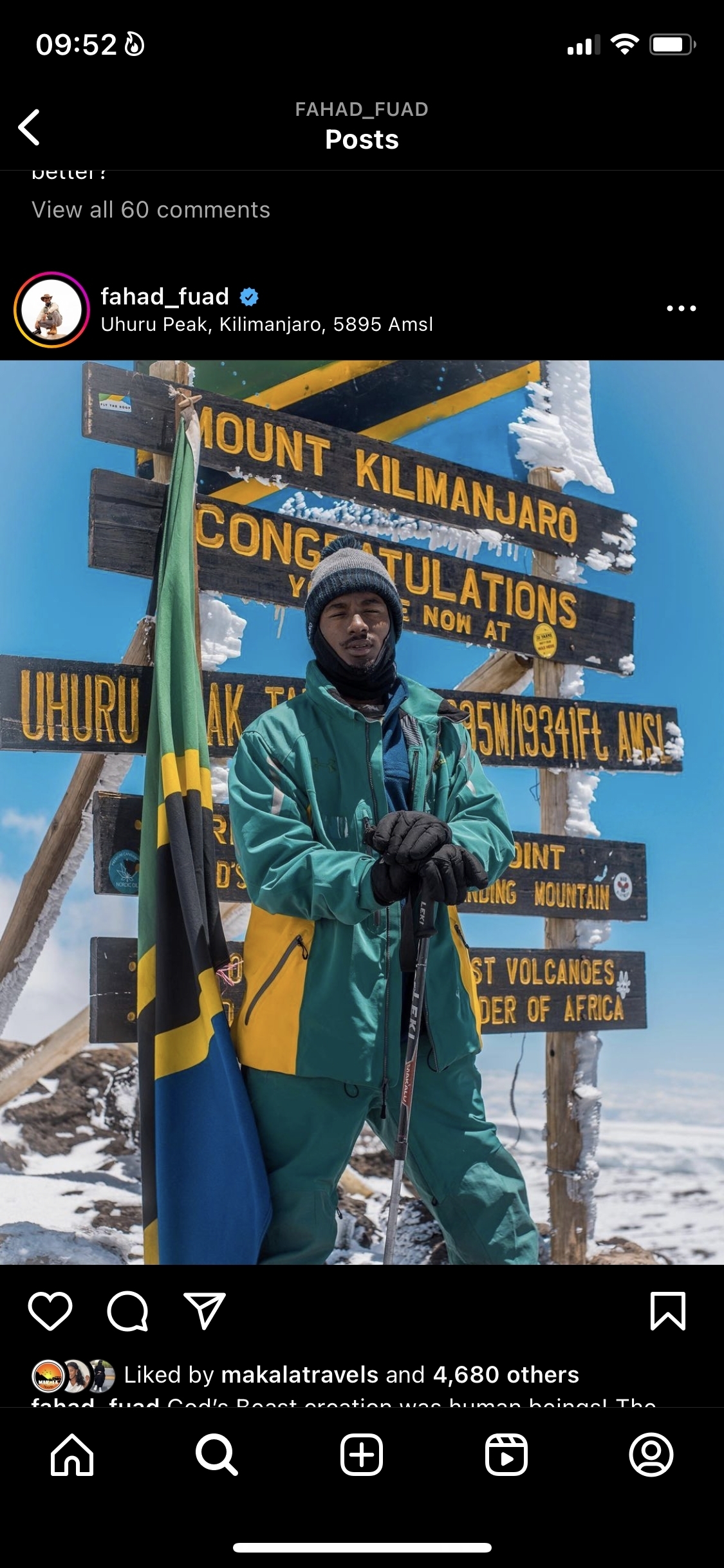 Person standing at Uhuru Peak signpost with snow in the background.
