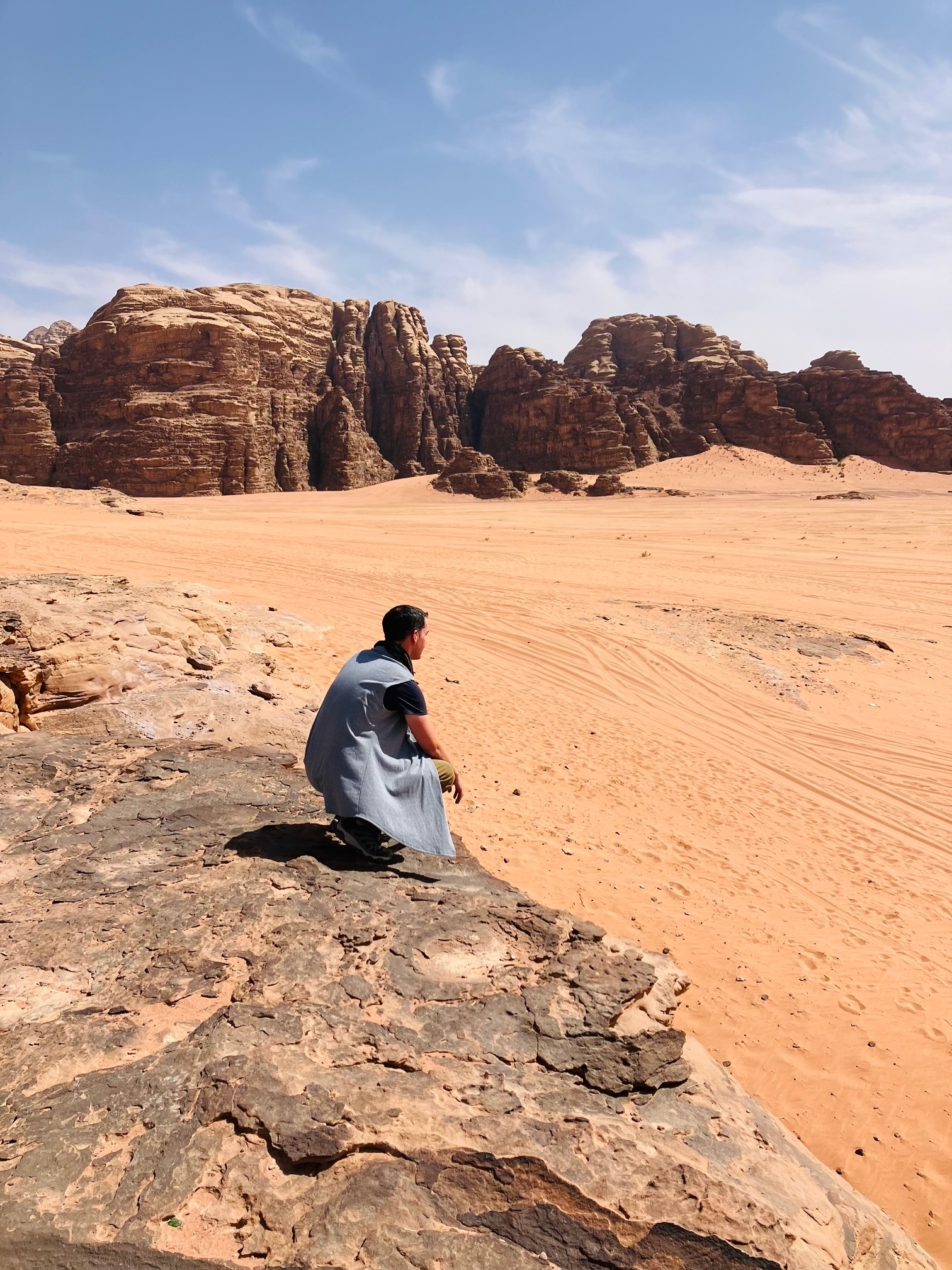 A person sitting on a rock in a desert landscape with rocky formations.