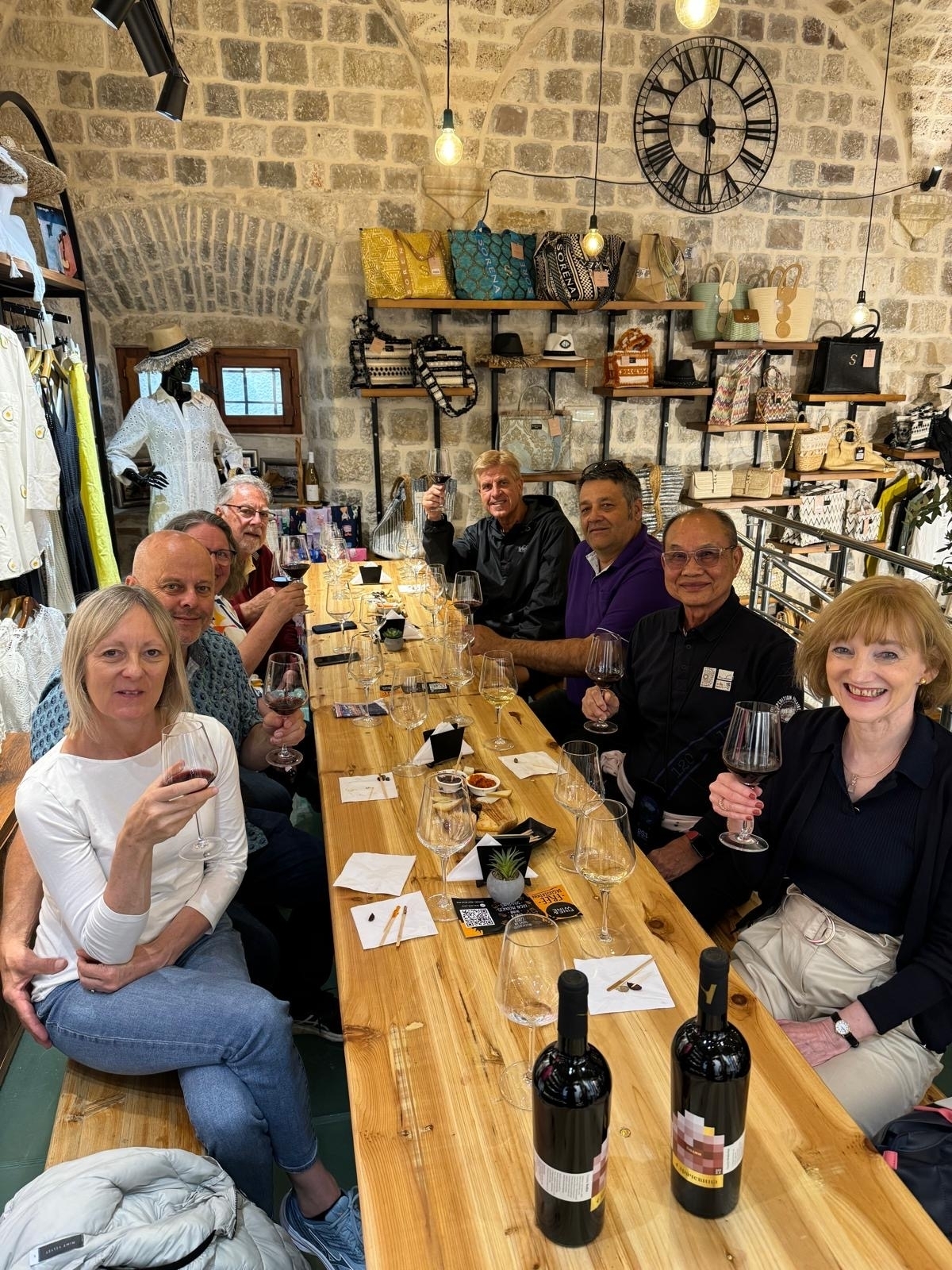 Group enjoying wine at a long table inside.