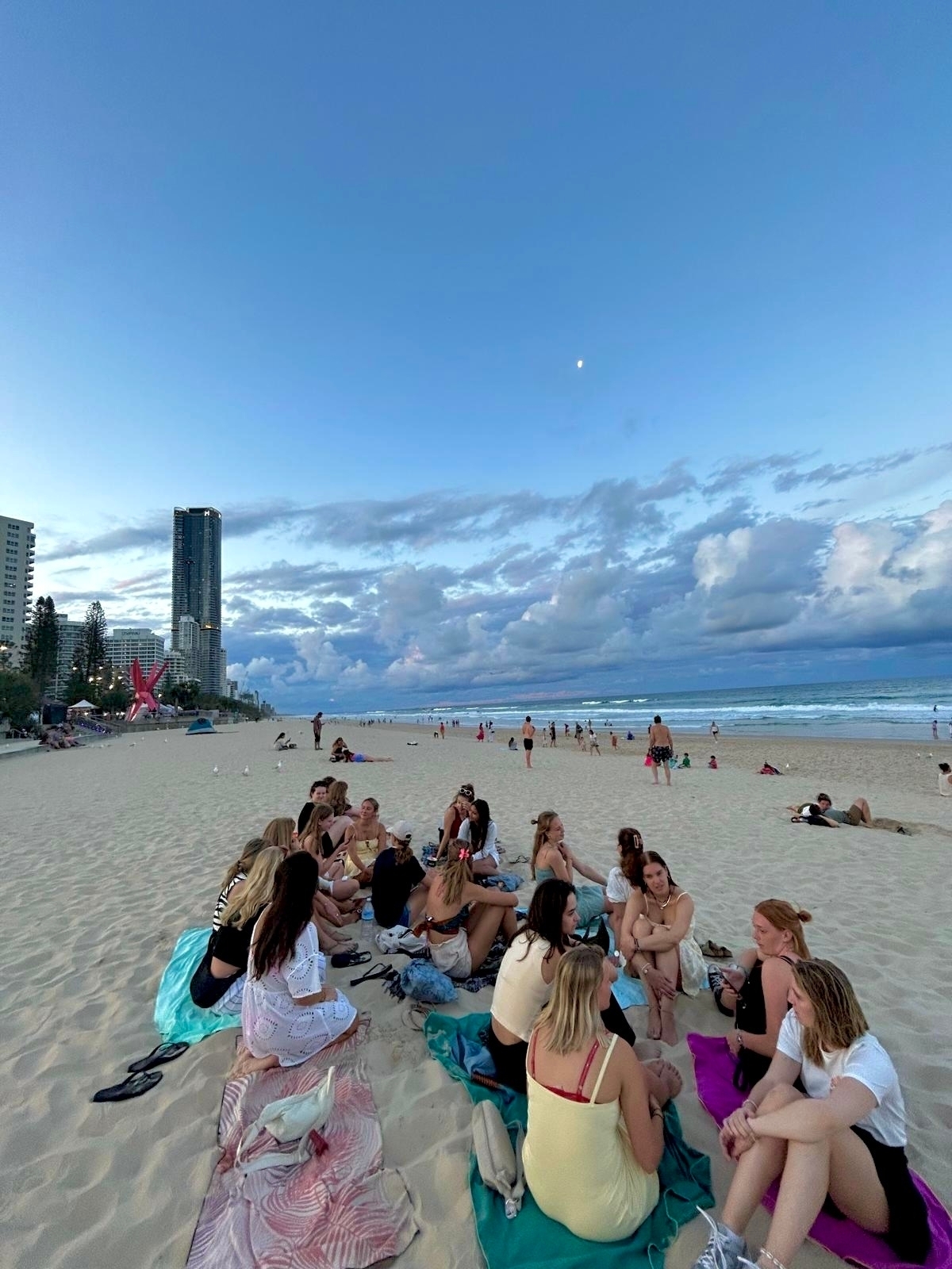 Beach scene with people relaxing and buildings in the background.