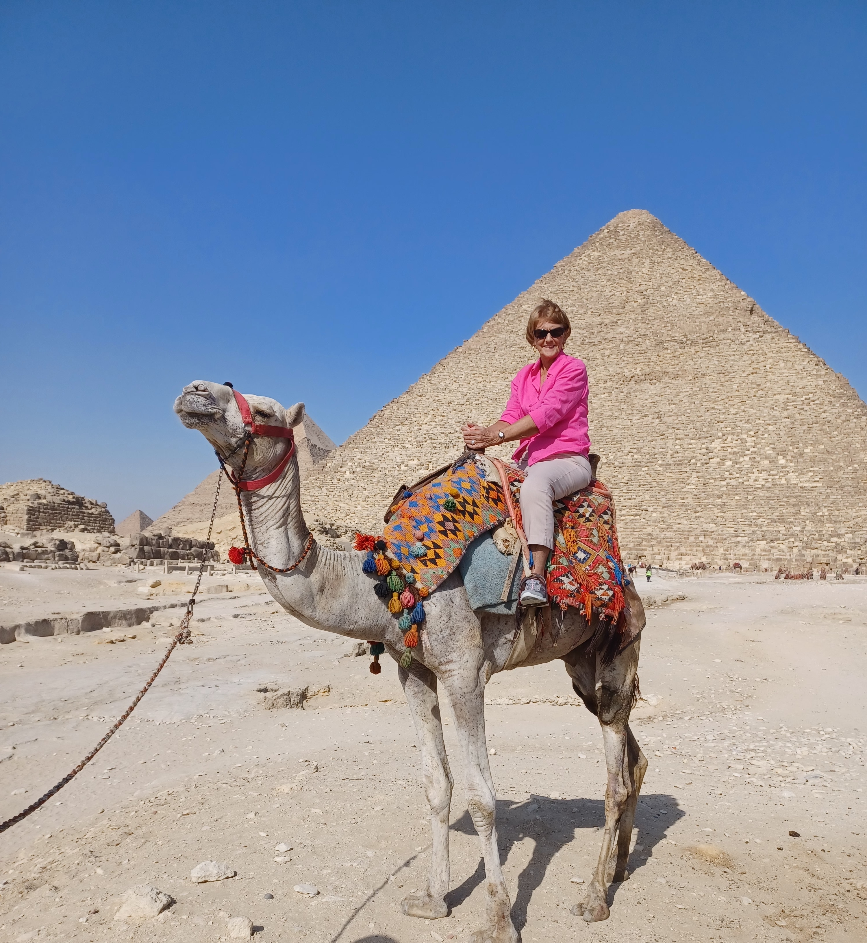 A person riding a camel in front of the pyramids in Egypt.