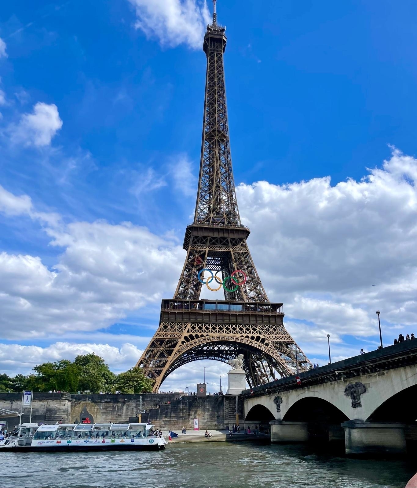 Eiffel Tower with Olympic rings against a blue sky.