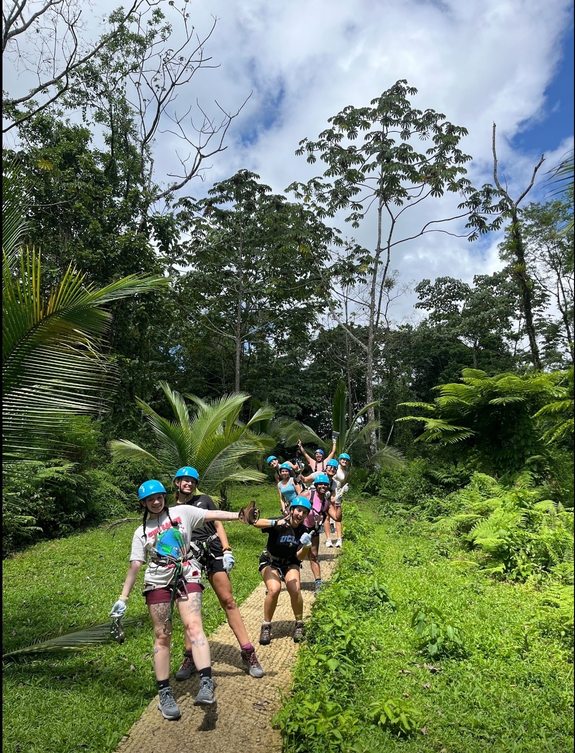 Group posing with helmets and harnesses in a jungle setting.