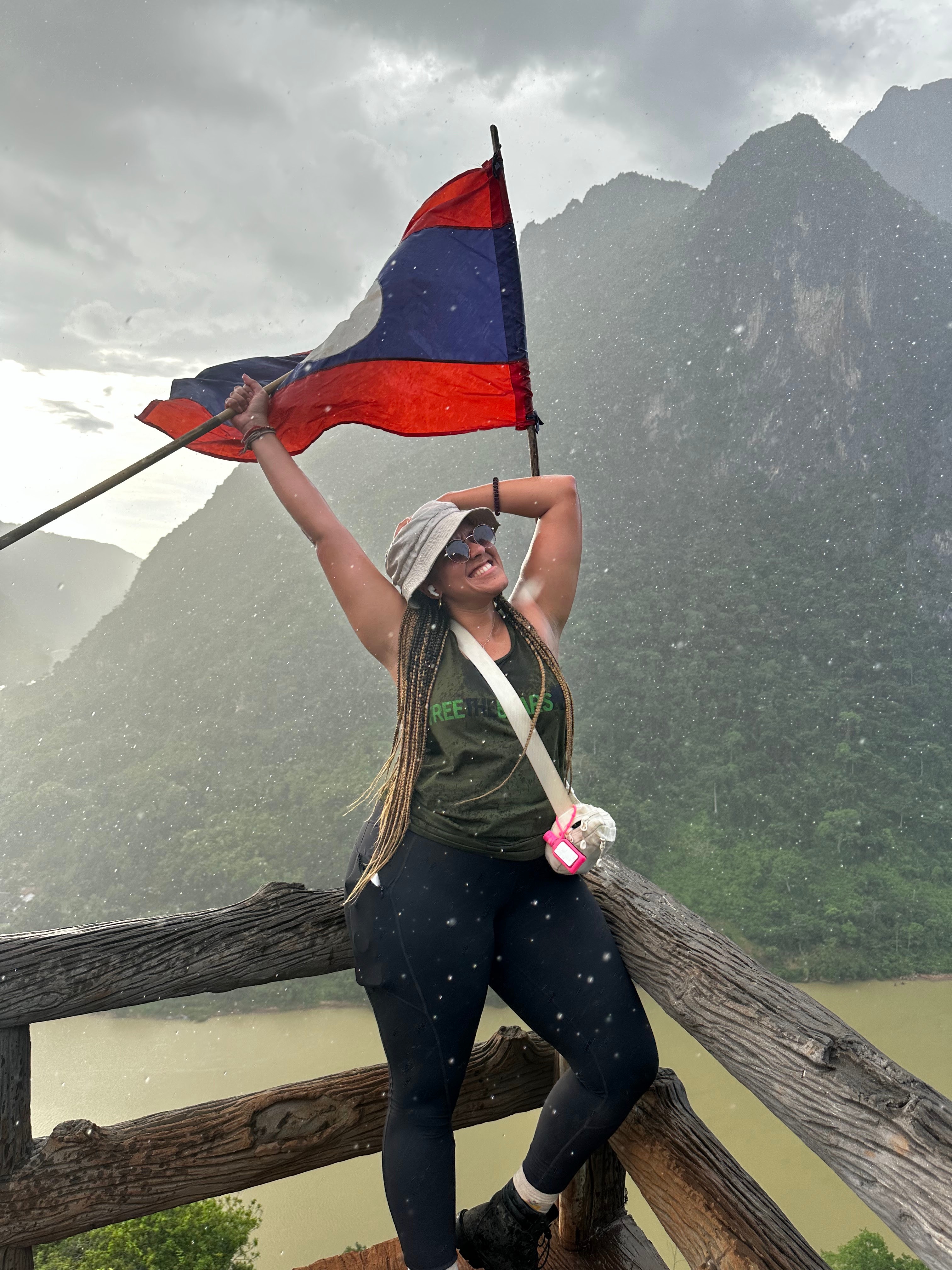Person holding a flag atop a mountain with scenic views.