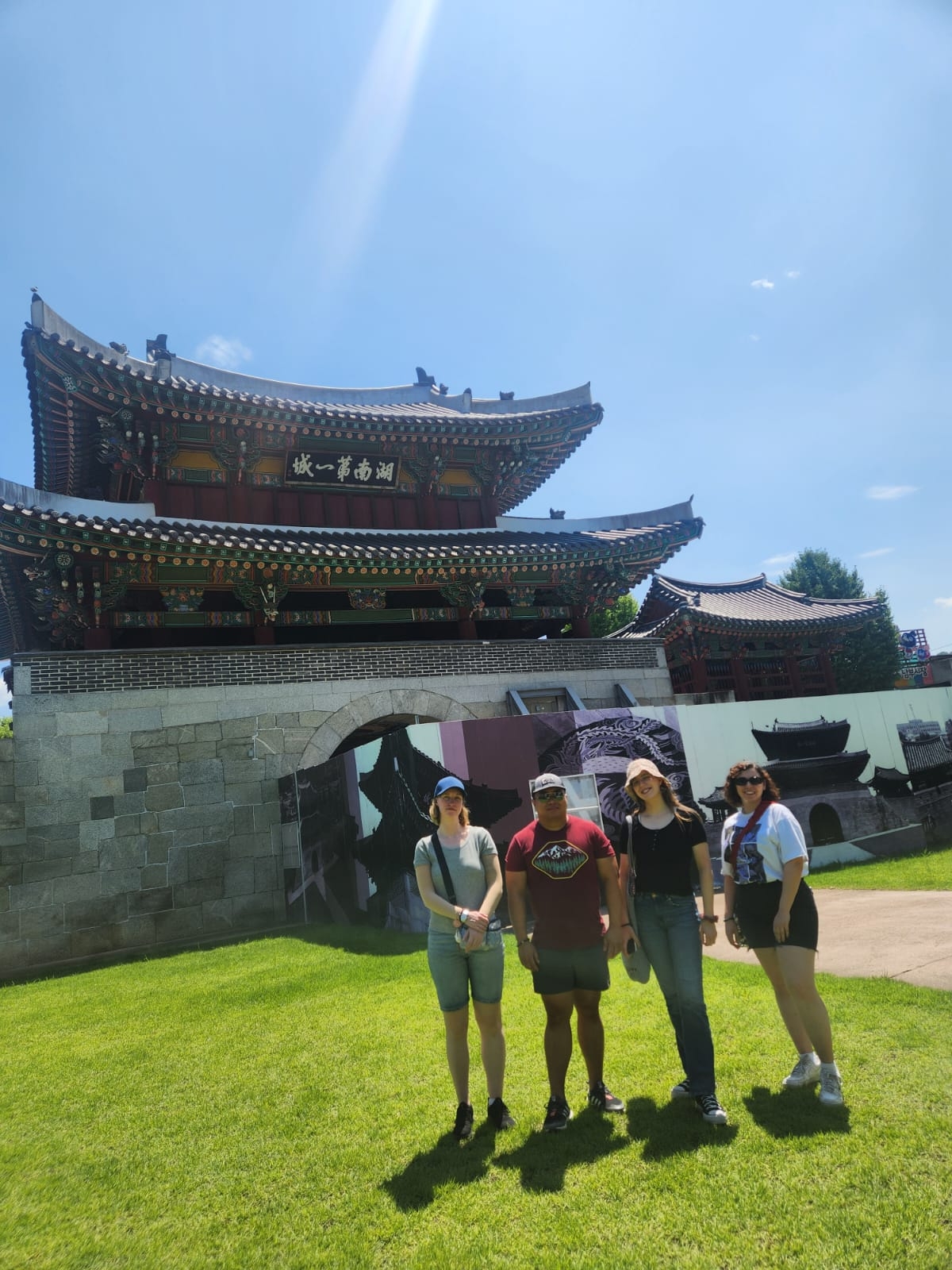 Group of people posing in front of a traditional Korean building.