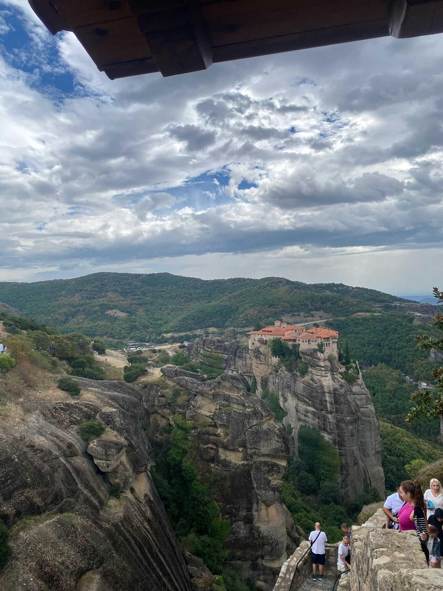 Monastery on a hill with lush greenery and cloudy sky.