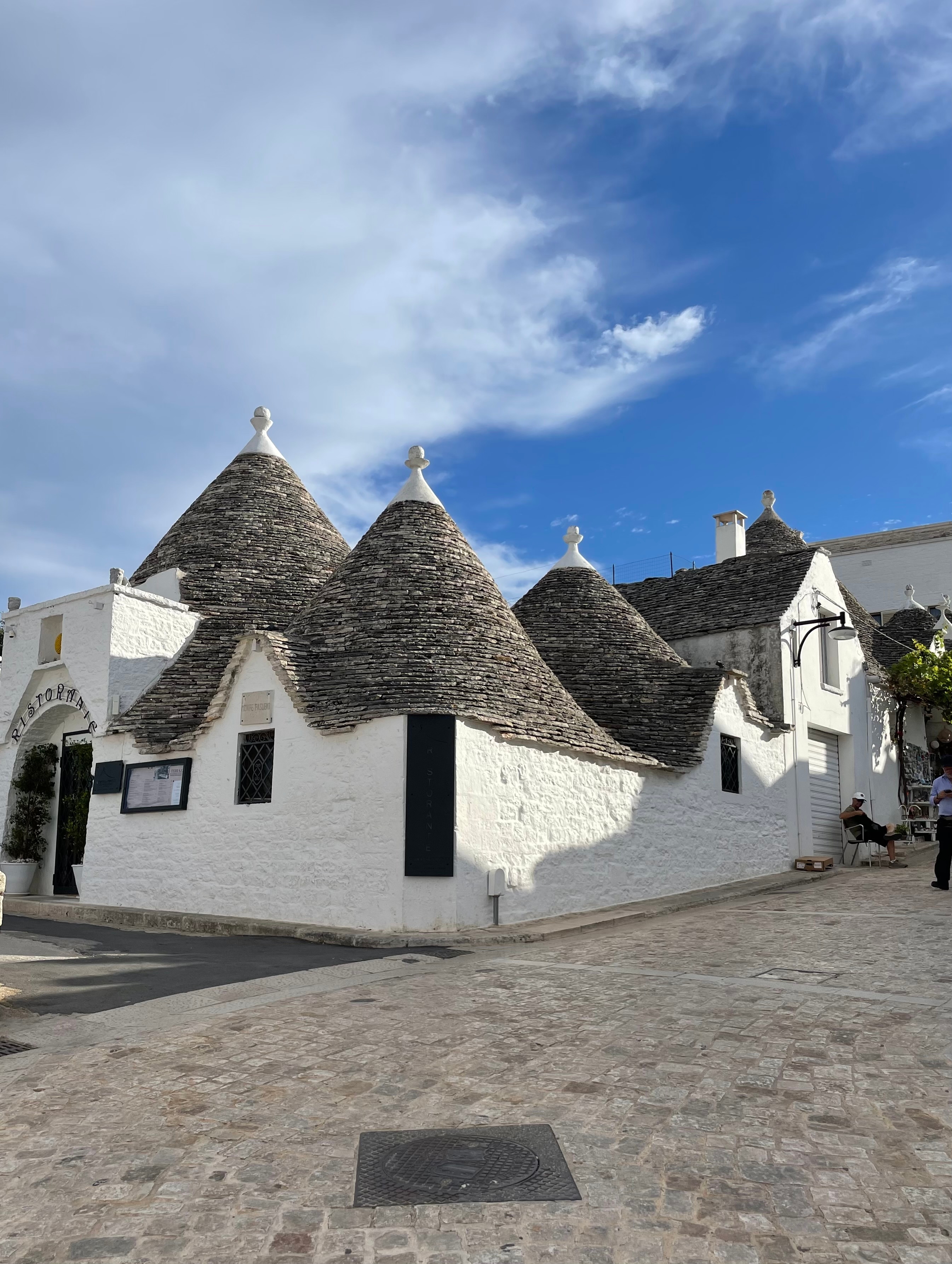 Traditional Trulli houses with conical roofs under a blue sky.