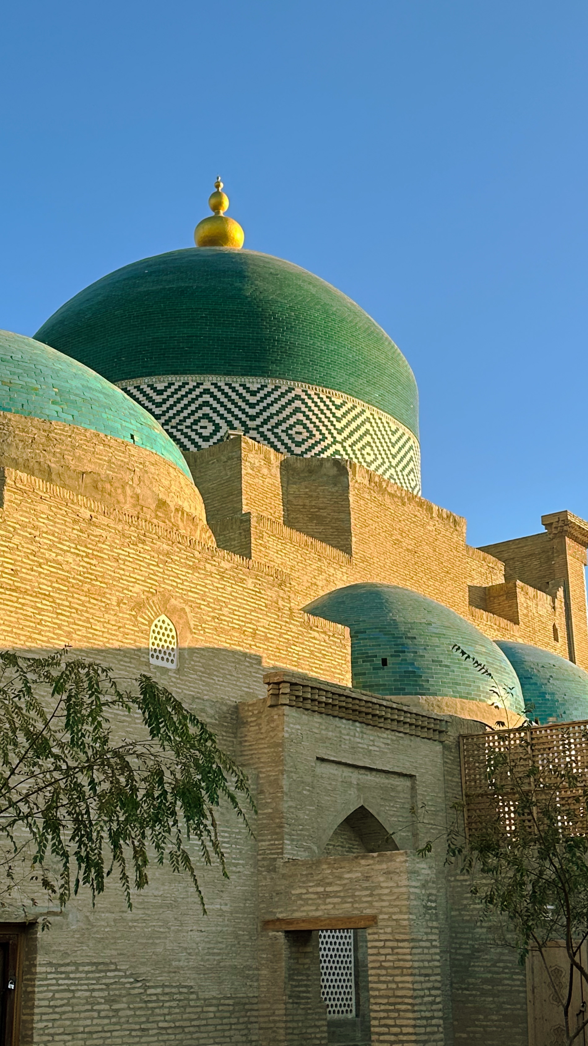 Colorful tiled domes and brickwork against a blue sky.