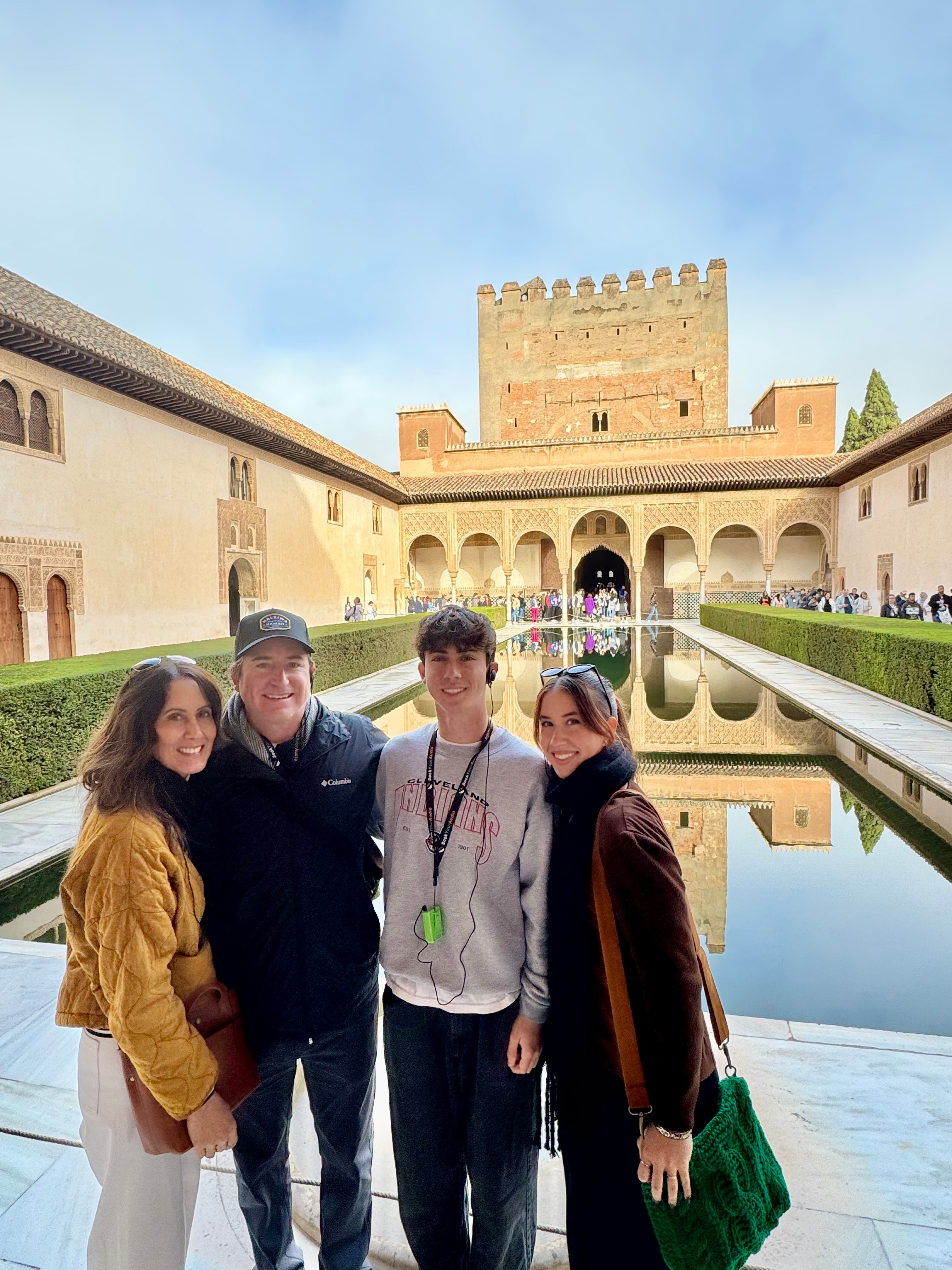 Family posing in front of a water reflection at a historic site.