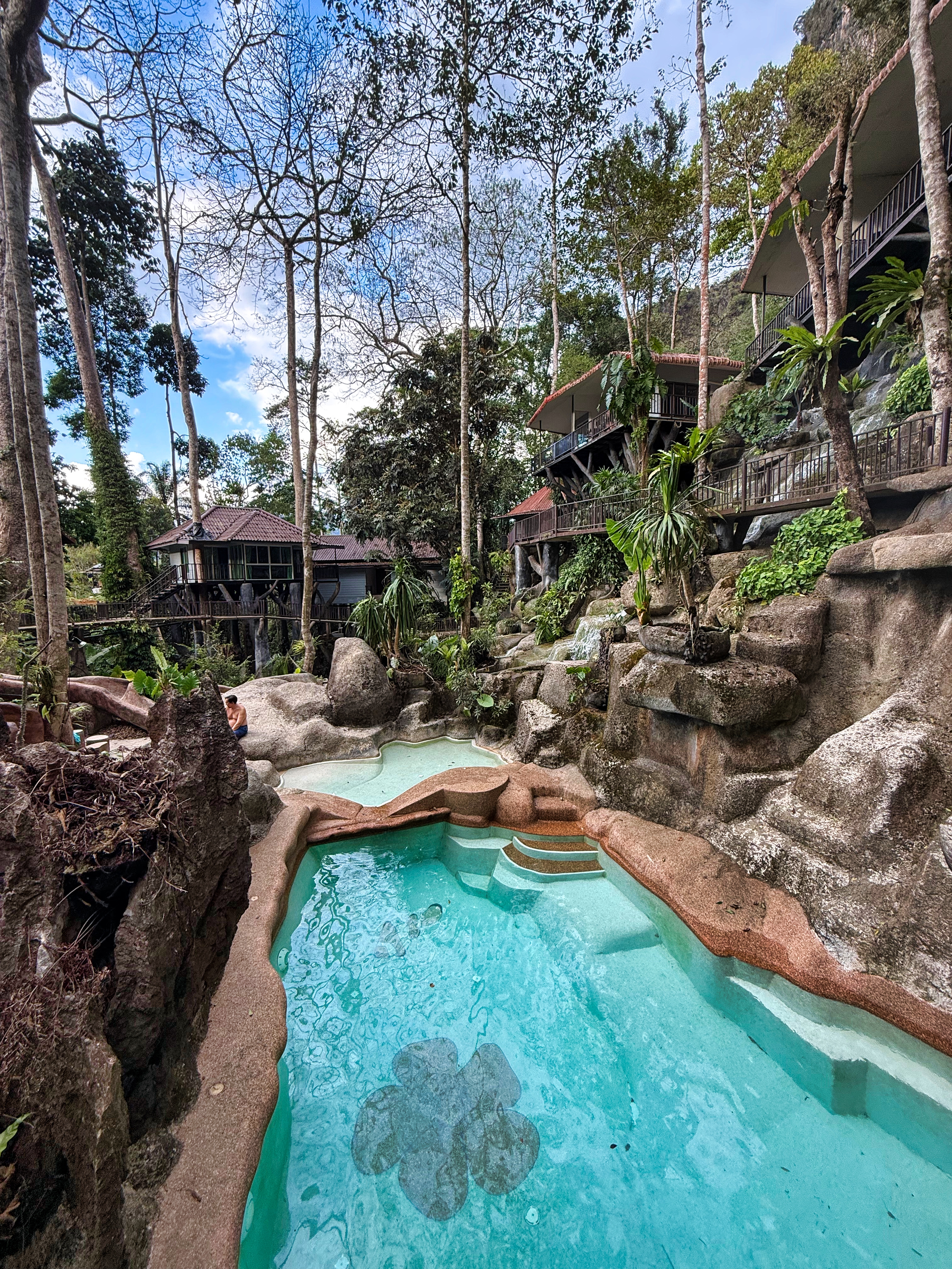 Natural rock formations with small pools and rustic buildings.
