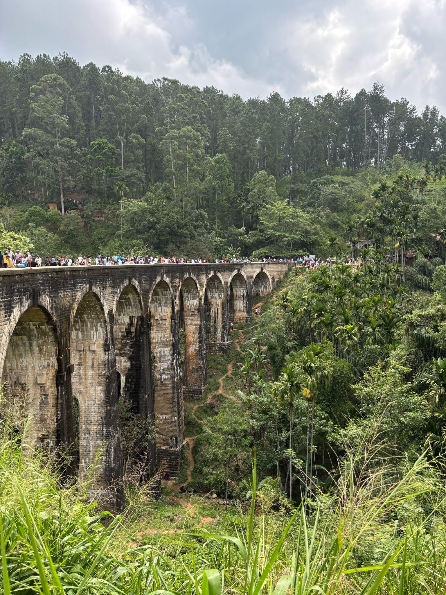 People on the Nine Arches Bridge in a lush, green area.