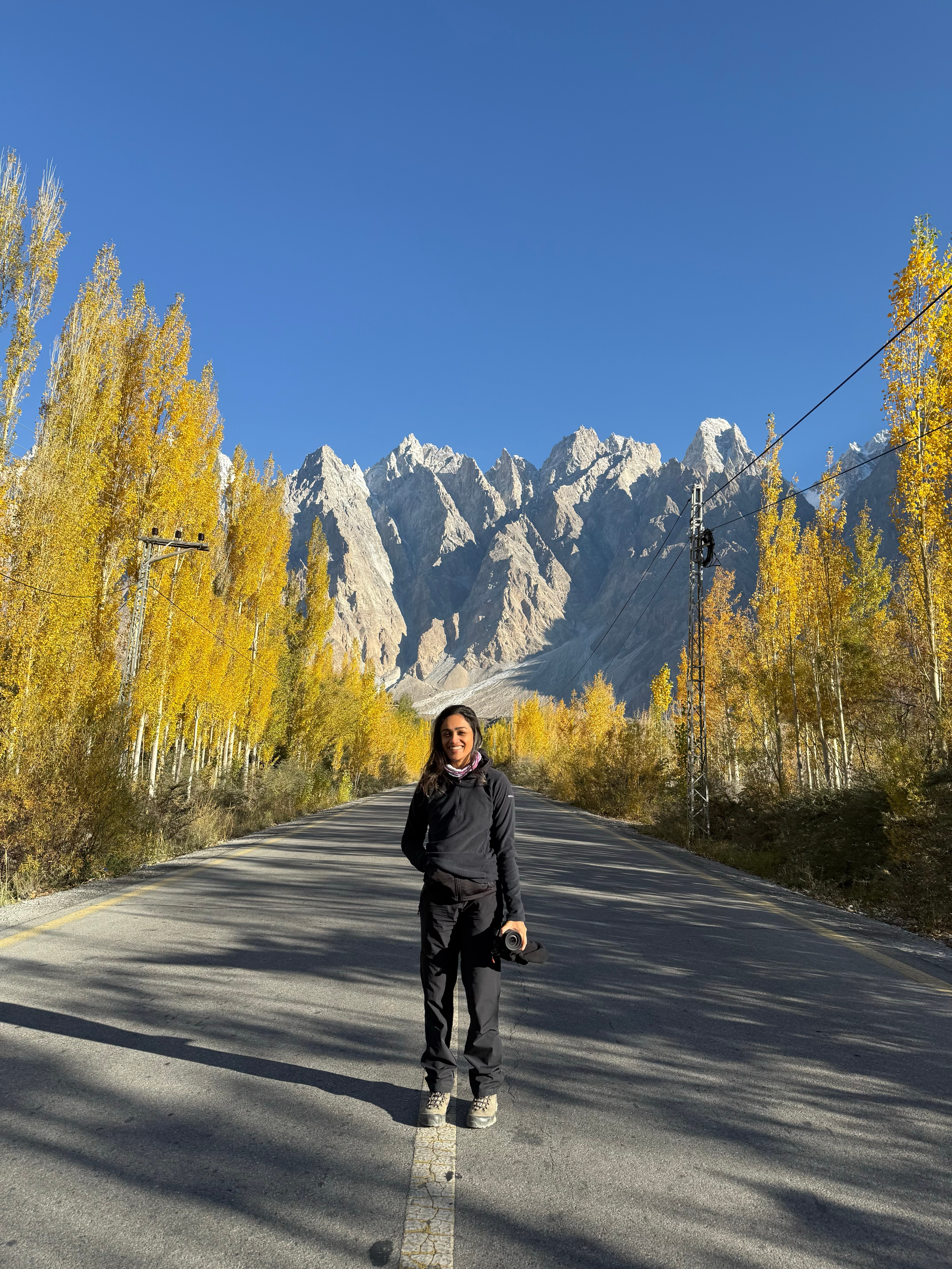 Person standing on a road with a backdrop of tall spiky peaks.