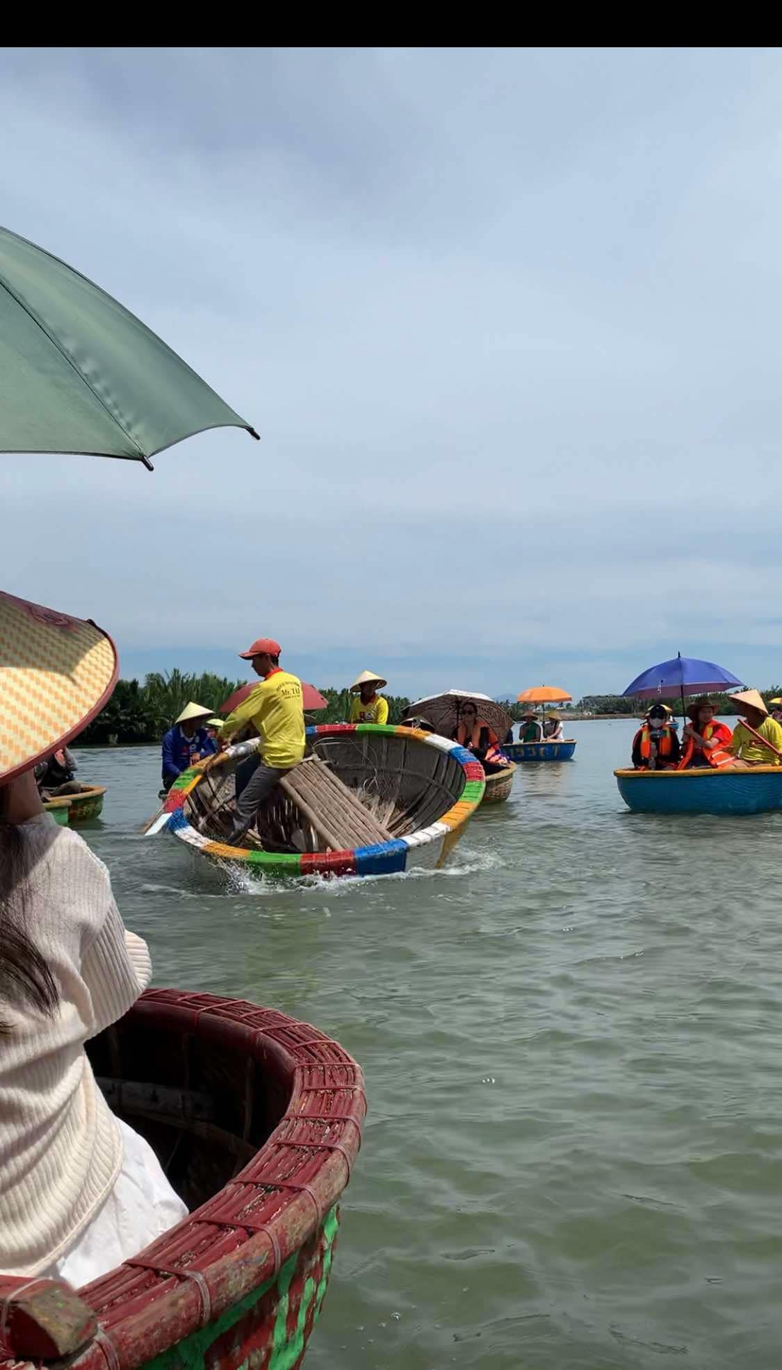 People in traditional hats riding round boats on a river.