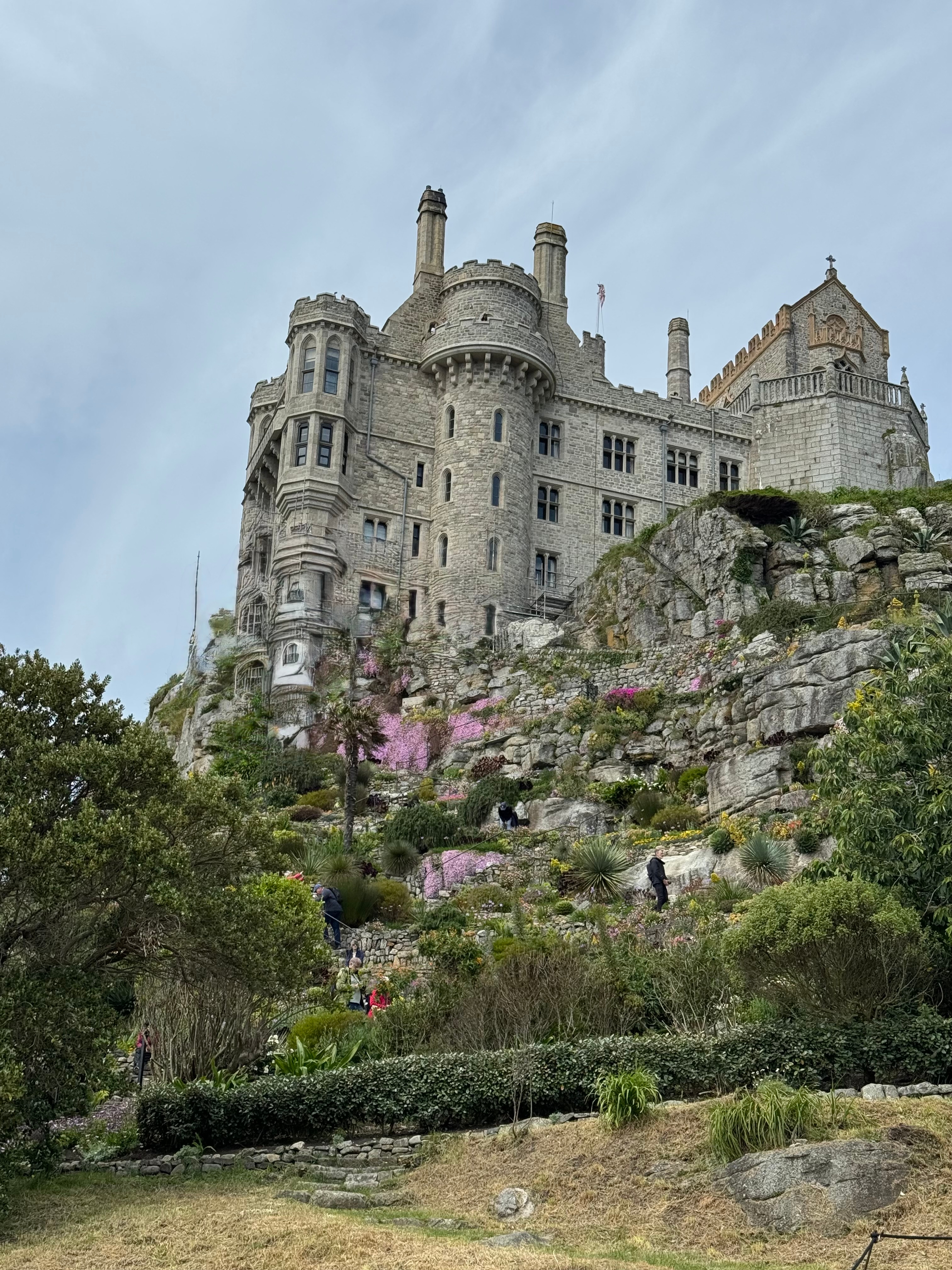 A magnificent castle built on a rocky hill with gardens below.