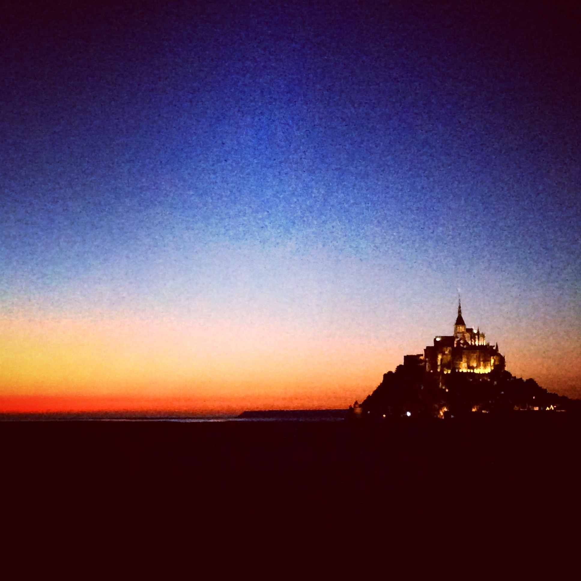 Scenic view of Mont Saint-Michel at sunset, beautifully silhouetted against the sky.