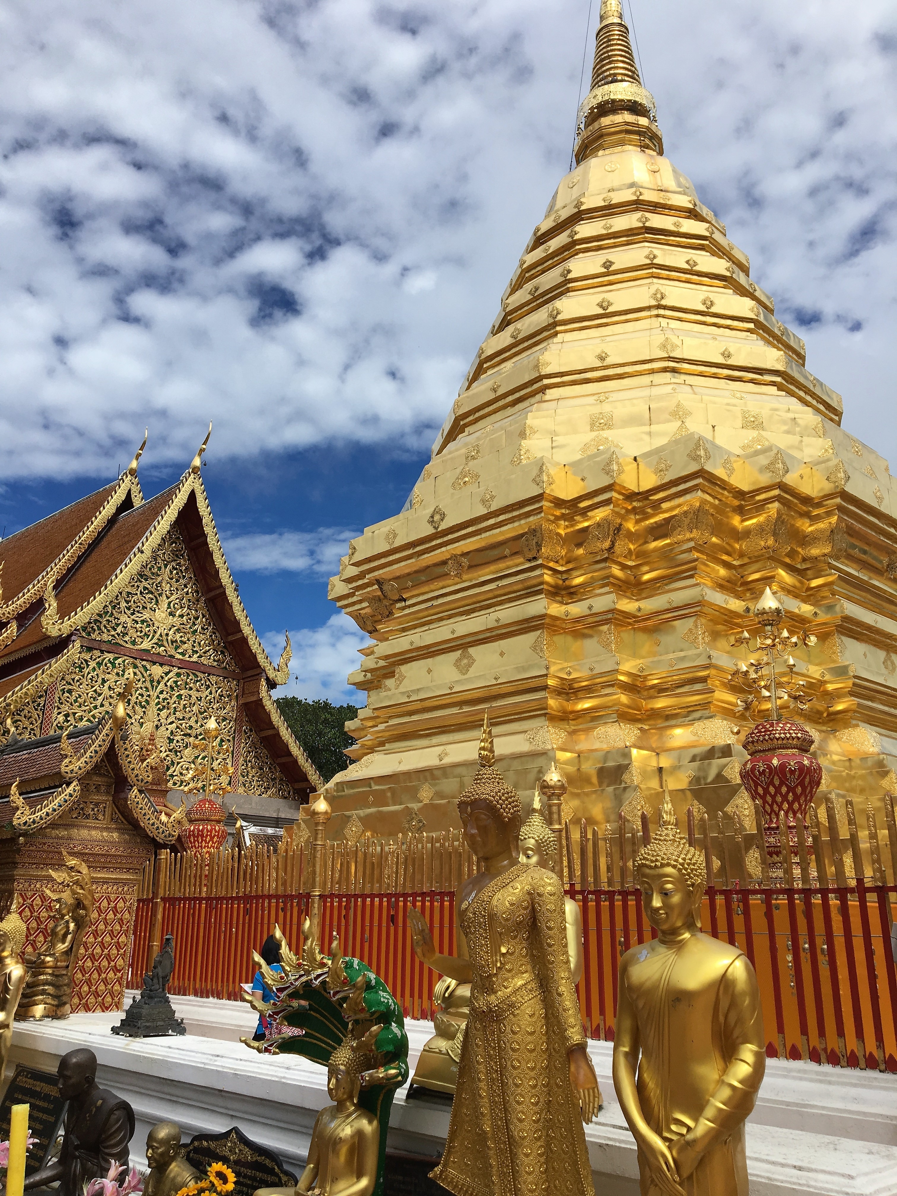Golden stupa and adorned temple with intricate carvings against a blue sky.