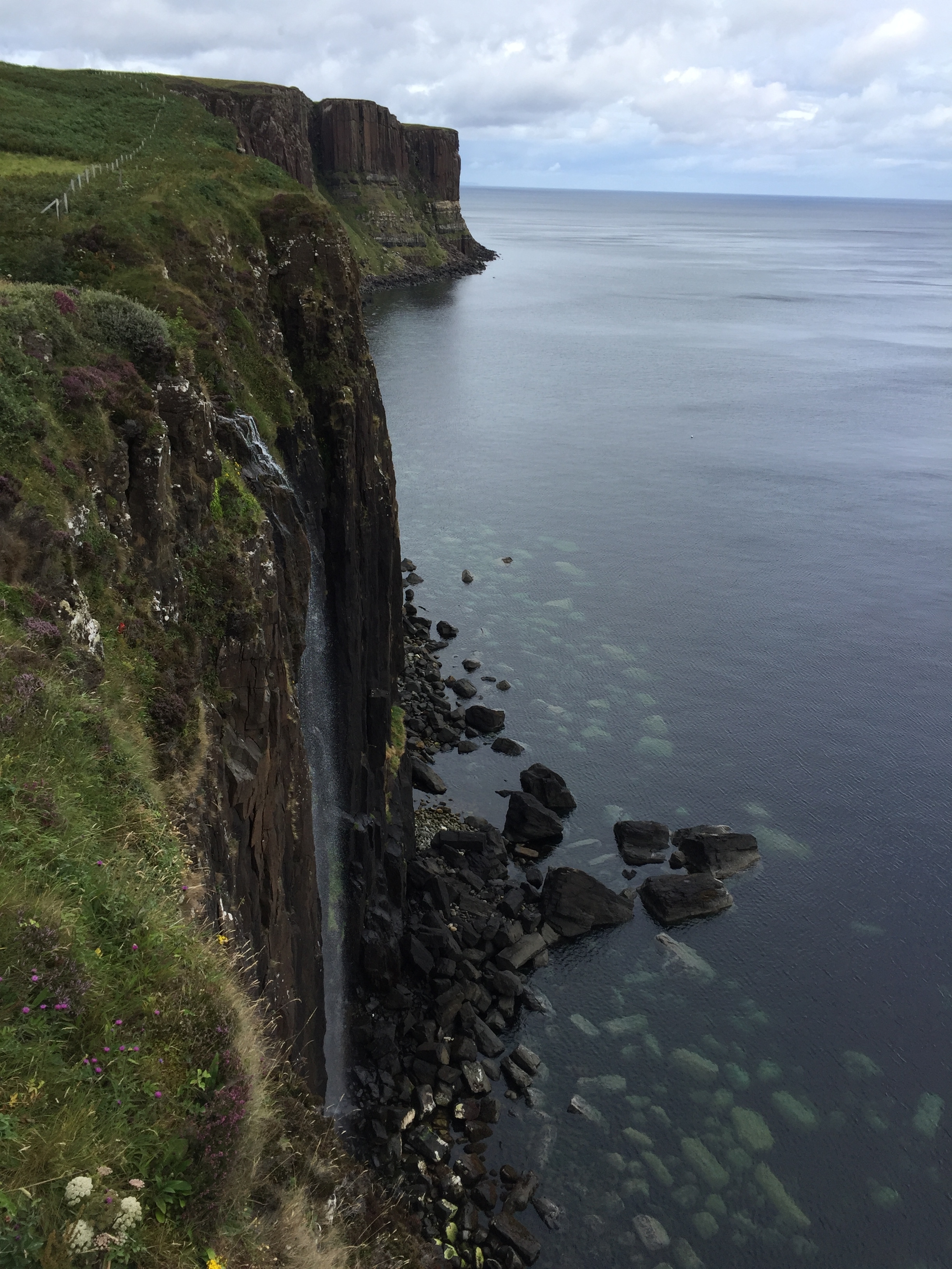 Cliffside view of a waterfall flowing into the ocean.