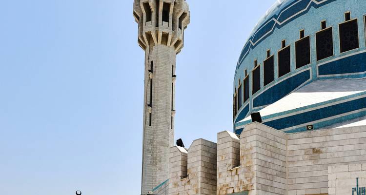 Mosquée bleue avec minaret blanc sous un ciel clair.