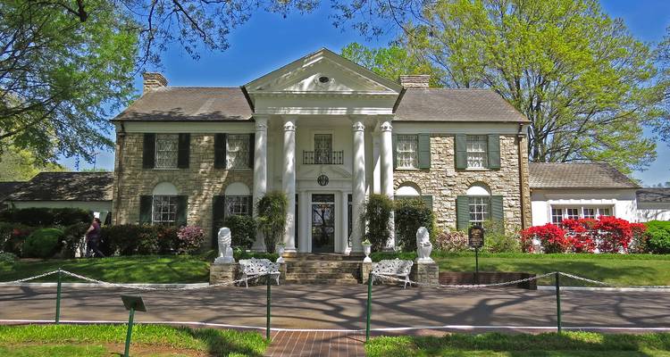 Front view of Graceland mansion surrounded by spring greenery and floral beds