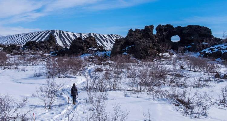 Persona caminando por un paisaje nevado con formaciones rocosas únicas.