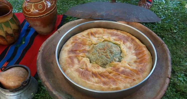 Pastel tradicional albanés con una corteza dorada sobre un paño decorativo.