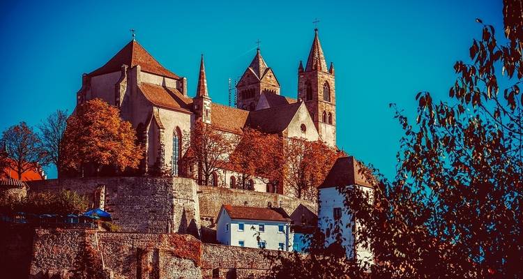 A majestic cathedral on a hill surrounded by autumn foliage.