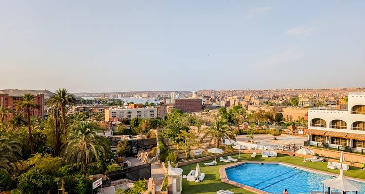 Hotel pool terrace overlooking a riverside cityscape framed by palms and low evening light