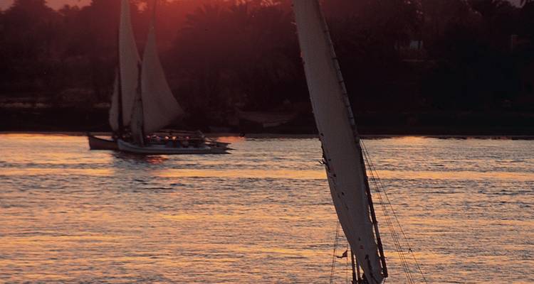 Sailboats on a river at dusk creating a serene atmosphere.