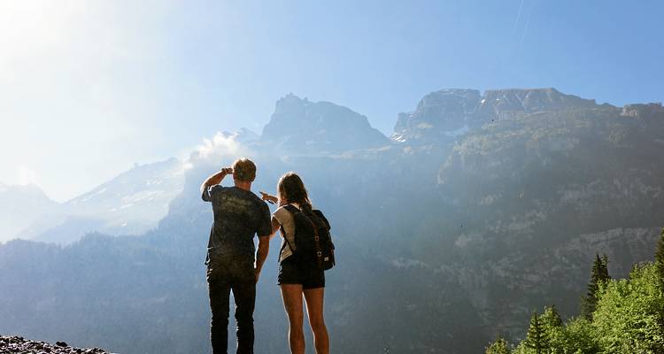 Deux randonneurs admirent les pics alpins lointains baignés dans la brume matinale.
