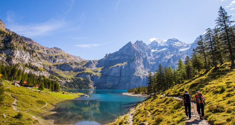 Les randonneurs suivent un sentier au bord du lac avec une eau turquoise et des pics alpins spectaculaires devant eux.
