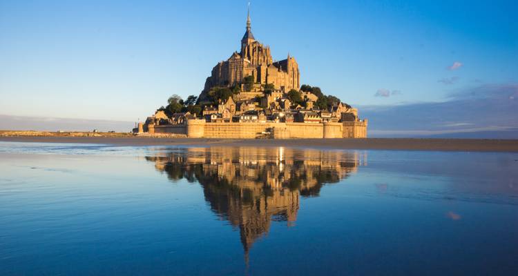 Mont Saint-Michel spiegelt sich bei Tagesanbruch im Wasser wider.