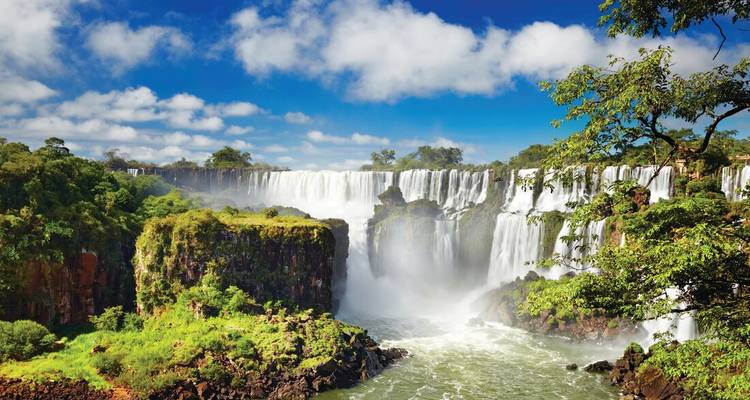 Majestic Iguazu Falls die door weelderig regenwoud stroomt onder een stralend blauwe hemel.