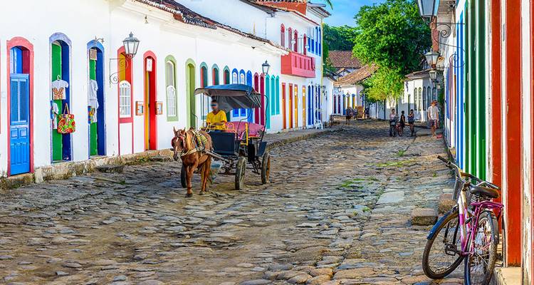 Colorful colonial street in Paraty with horse-drawn carriage on cobblestones.