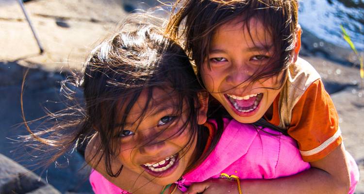 Dos niños sonriendo alegremente con agua en el fondo.