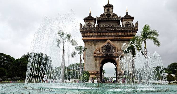 Puerta de la Victoria con fuente de agua y palmeras.