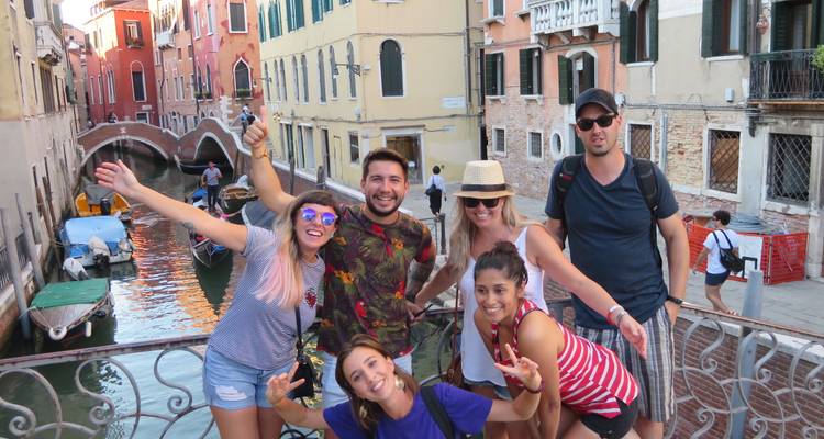 Groupe de touristes posant sur un pont à Venise avec des canaux.