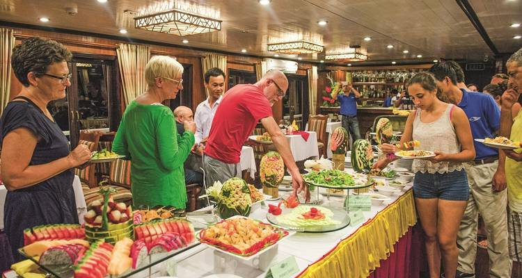 Un grupo de personas alrededor de una mesa de buffet con varios platos.