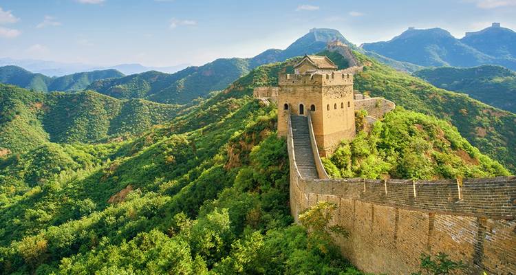 Een gedeelte van de Chinese Muur die over groene bergen loopt.
