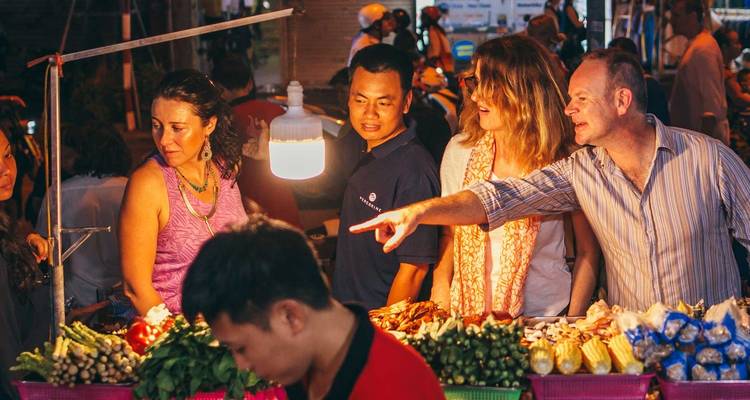 Group of people examining food items at a vibrant night market.